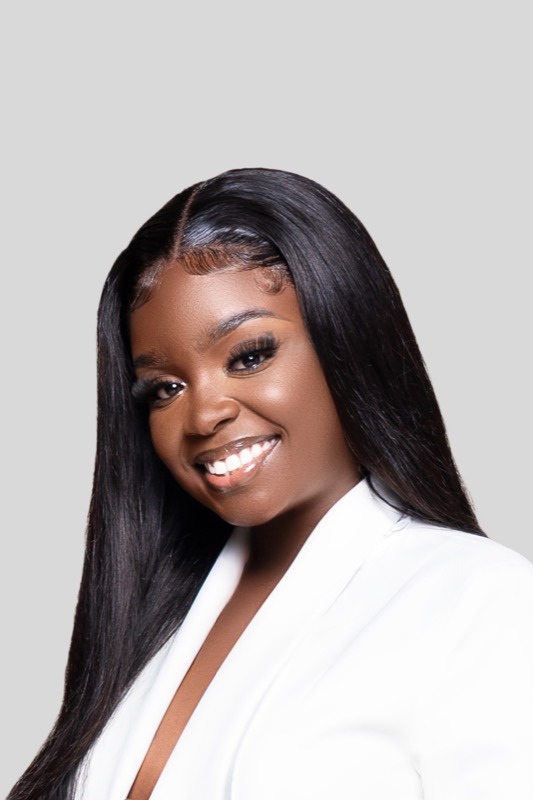 Janiece smiling softly in a white blazer