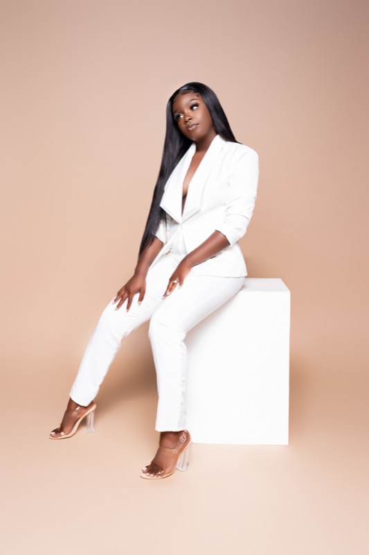 Janiece seated in a white suit, full length