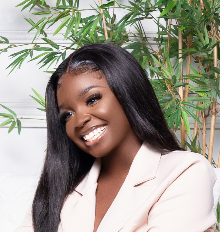 Janiece smiling warmly with a plant backdrop