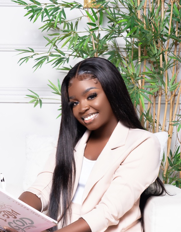 Janiece smiling with a journal, plant backdrop