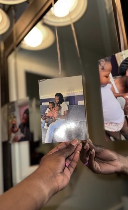 Holding up printed family photos in front of a mirror lined with more memories