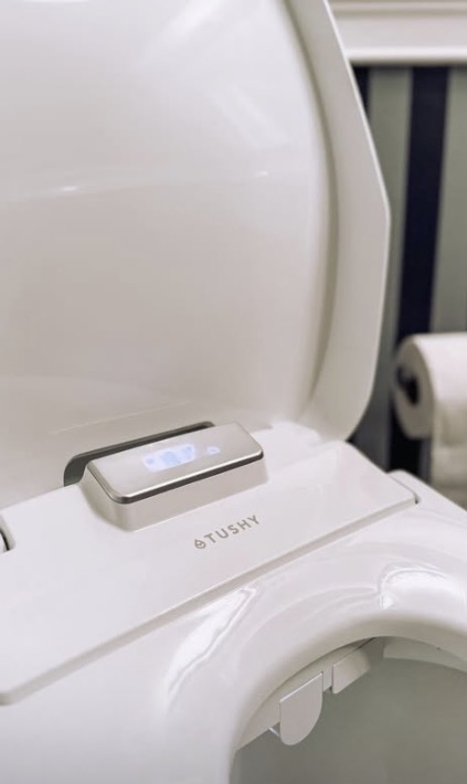 Close-up of a Tushy bidet attachment in a bathroom