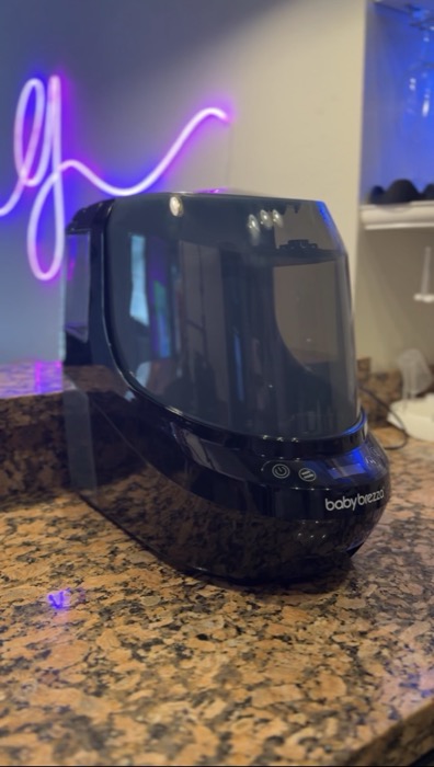 Baby Brezza humidifier on a counter lit by a neon monogram sign